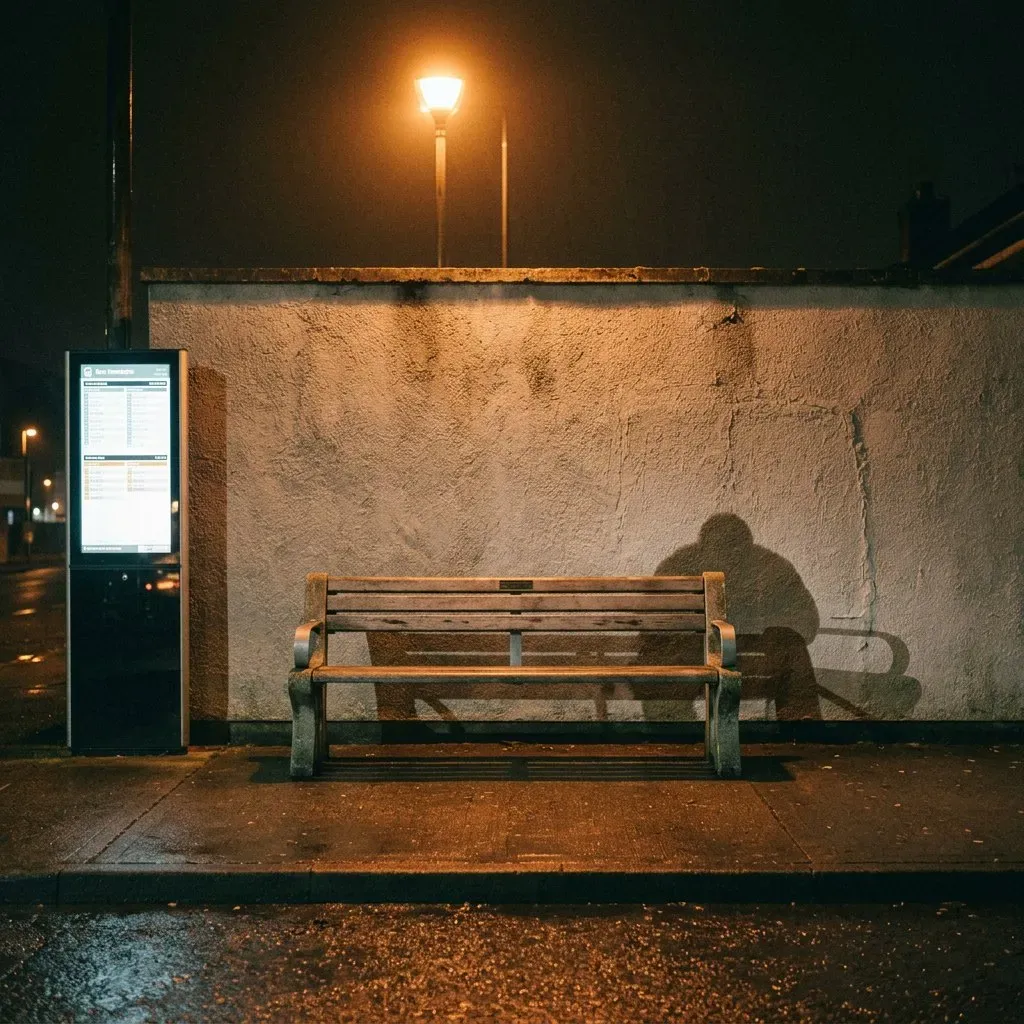 A night bus stop: an empty wooden bench against a lit wall, and on the wall the seated shadow of a man that the bench does not explain.