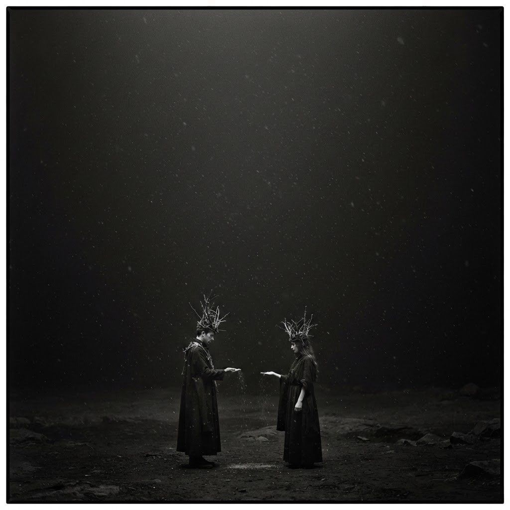 Two small crowned figures stand facing each other in a vast dark misty waste, passing a scrap of paper between them.